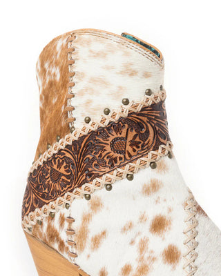 Close-up of a cowhide boot with intricate leatherwork on a white background