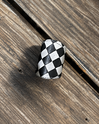 A small black and white checkered scarf slide placed on weathered brown wooden deck boards.