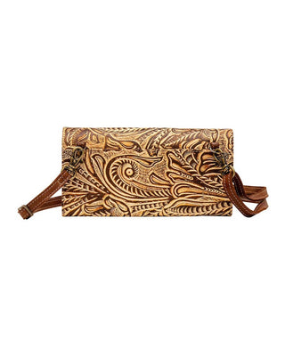 A tooled leather crossbody bag with intricate floral and paisley embossed patterns in shades of brown and tan, featuring a matching leather strap and gold-tone hardware, shown against a plain white background.