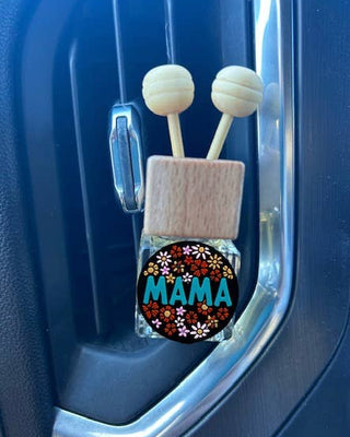 Car air freshener with 'MAMA' and floral design in a blue car vent.