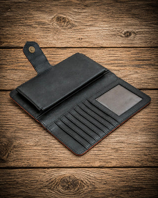 A black leather wallet shown open on a rustic wooden surface, featuring card slots, a small slip pocket, and an ID window.