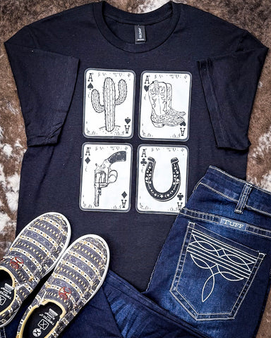 The Four Aces Graphic Tee displayed on cowhide along with shoes and jeans.