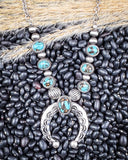 Necklace on black pebbles and wheat.