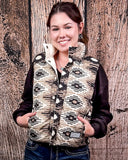 A girl modeling the Jane Hooey Reversible Puffer Vest with both hands in her pockets. She is standing in front of a wood back drop.