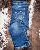 Folded blue jeans on a brown and white patterned surface