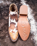 Cow print shoe with rubber sole on a textured surface