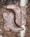 Pair of taupe cowboy boots with rhinestone details on a textured surface