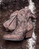 Pair of brown faux suede boots with rhinestone details on a textured surface