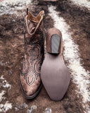 Brown cowboy boot with decorative studs on a textured surface