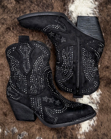 Black cowboy boots with rhinestone details on a textured surface