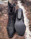 Black studded ankle boot on a textured surface