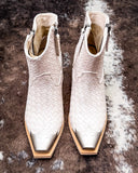 Pair of white woven ankle boots on a textured brown surface