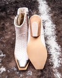 White textured ankle boot and beige sole on a textured brown surface