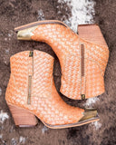 Pair of woven tan ankle boots with gold accents on a textured surface