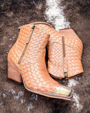 Pair of woven tan ankle boots on a textured brown surface