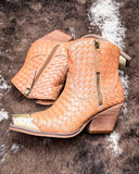 Tan woven ankle boots with gold zipper on a textured brown background