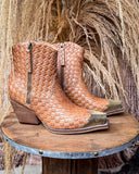 Pair of woven brown cowboy boots on a wooden stand with a rustic background