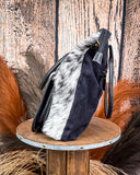 Black bag with fur accents on a wooden stool against a rustic wooden background