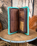 Brown leather wallet with turquoise trim on a wooden surface