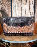 The Duskline Embossed Crossbody Purse displayed on a wooden table with wheat in the back ground, sitting in front of a wood back drop.