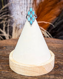 Achilles Adjustable Genuine Turquoise Ring displayed on wooden table.