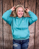 Person wearing a turquoise hoodie with a wooden background