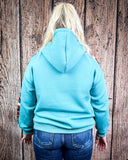 Person wearing a light blue hoodie with a wooden background