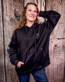 Person wearing a black hoodie with a logo against a wooden background