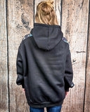 Person wearing a black hoodie with a wooden background