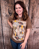 Woman wearing a graphic t-shirt with a design of a bronc and boots in front of a wooden wall.
