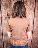Person wearing a brown t-shirt against a wooden wall