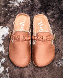 Pair of brown mules with braided design on a textured surface
