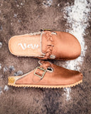 Pair of brown faux suede shoes with a buckle on a textured surface
