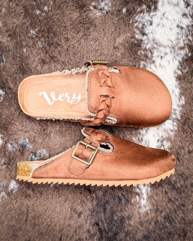 Pair of brown faux suede shoes with a buckle on a textured surface
