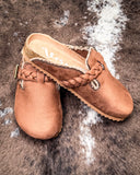 Pair of brown mules with braided design on a textured surface