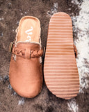 Brown clog shoe with textured sole on a textured surface