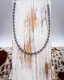 Necklace with dark beads on a wooden surface with a cowhide pattern
