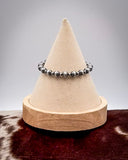 Beaded bracelet on a cone-shaped display against a plain background
