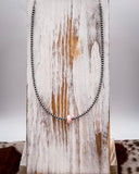 Necklace with pink conch on a wooden surface