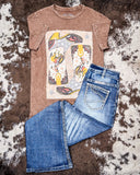Brown t-shirt with graphic design and blue jeans on a textured surface