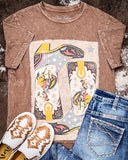 Brown t-shirt with graphic design, blue jeans, and white shoes on a textured surface