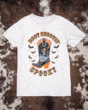 White t-shirt with Halloween-themed design featuring a boot and ghost on a textured brown background.