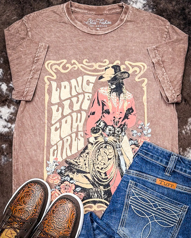 Brown t-shirt with cowboy graphic and text, paired with jeans and sneakers on a textured background