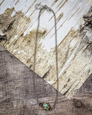 Necklace with a turquoise pendant on a wooden surface