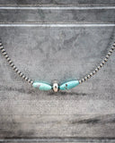 Necklace with turquoise beads and silver chain on a textured gray background