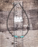 Necklace with a turquoise pendant on a wooden surface with a ruler for scale.