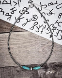 Necklace with turquoise beads on a wooden surface with a paper background