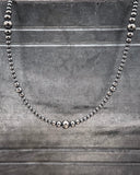 Silver beaded necklace on a textured gray background