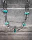 Necklace with turquoise stones and silver beads on a gray background