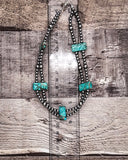 Necklace with turquoise stones on a wooden surface with a ruler for scale.